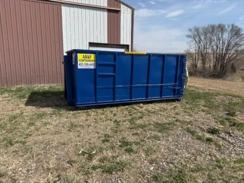 An empty blue ASAP Containers roll-off dumpster ready for drop off in Omaha, NE